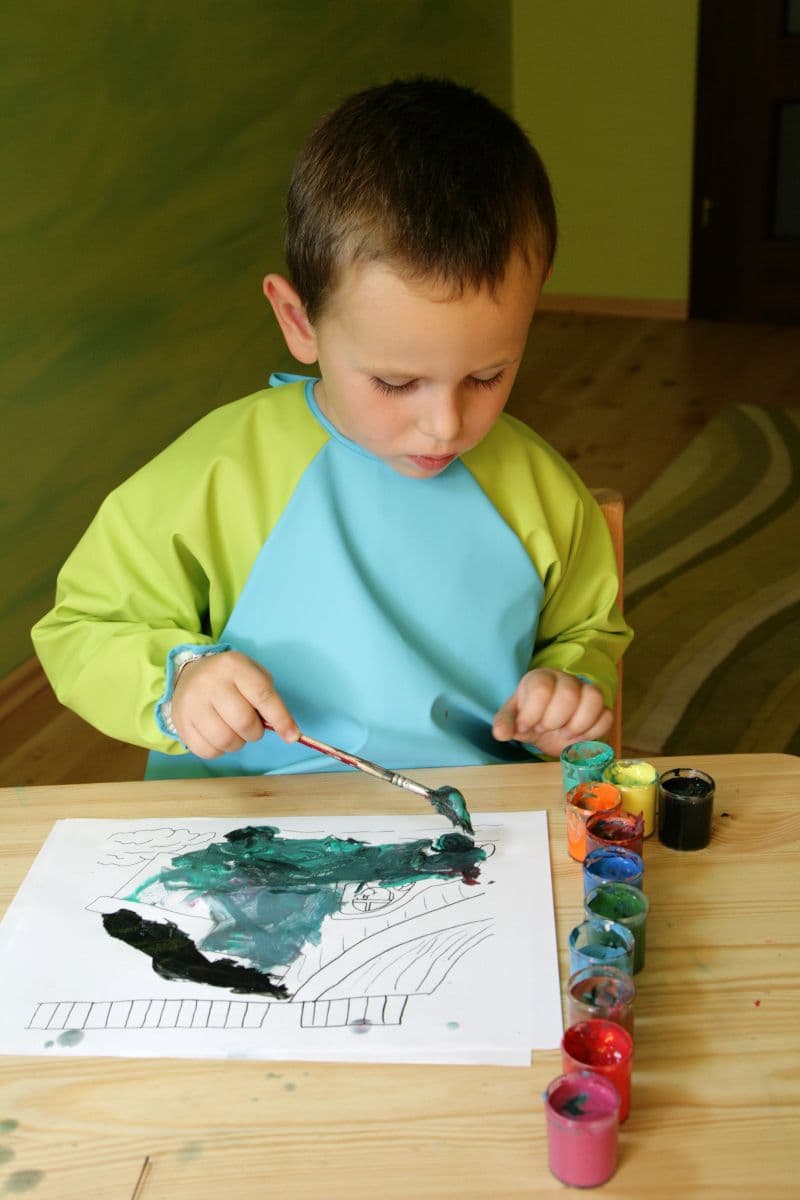 Criança a pintar com um pincel numa atividade de artes plásticas