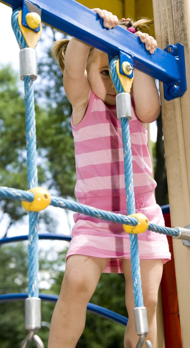 Criança a subir numa estrutura de escalada num parque infantil